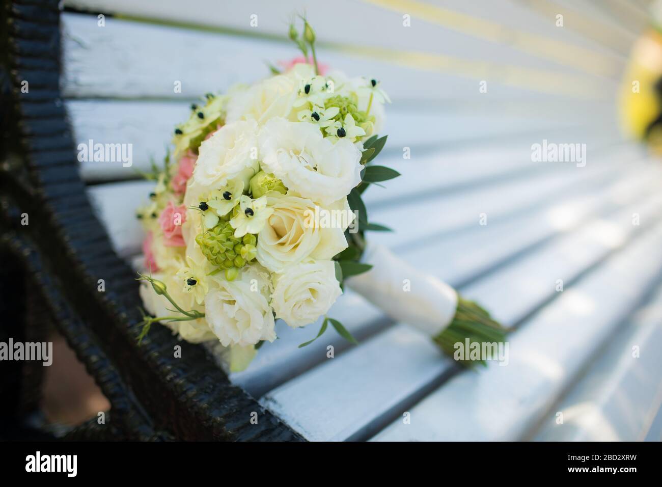 Hochzeitsringe, die auf der Holzoberfläche neben dem Hochzeitsbouquet liegen. Nahaufnahme. Stockfoto