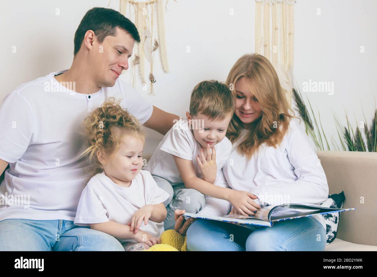 Glückliche Eltern lesen mit Kindern. Ein glückliches Familienkonzept Stockfoto