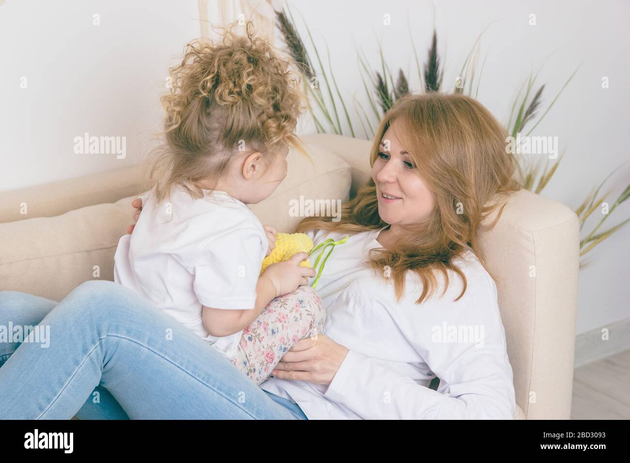 Lockiges Mädchen umarmt ihre Mutter. Lifestyle Happy Family Konzept Stockfoto