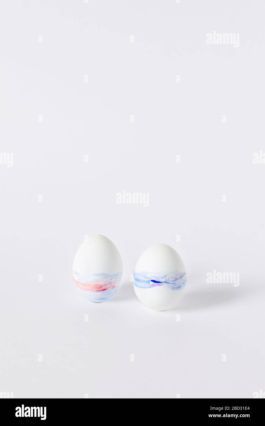 Vertikales Osterbild. Zwei mit Aquarell bemalte Eier auf einem weißen Tisch. Stockfoto