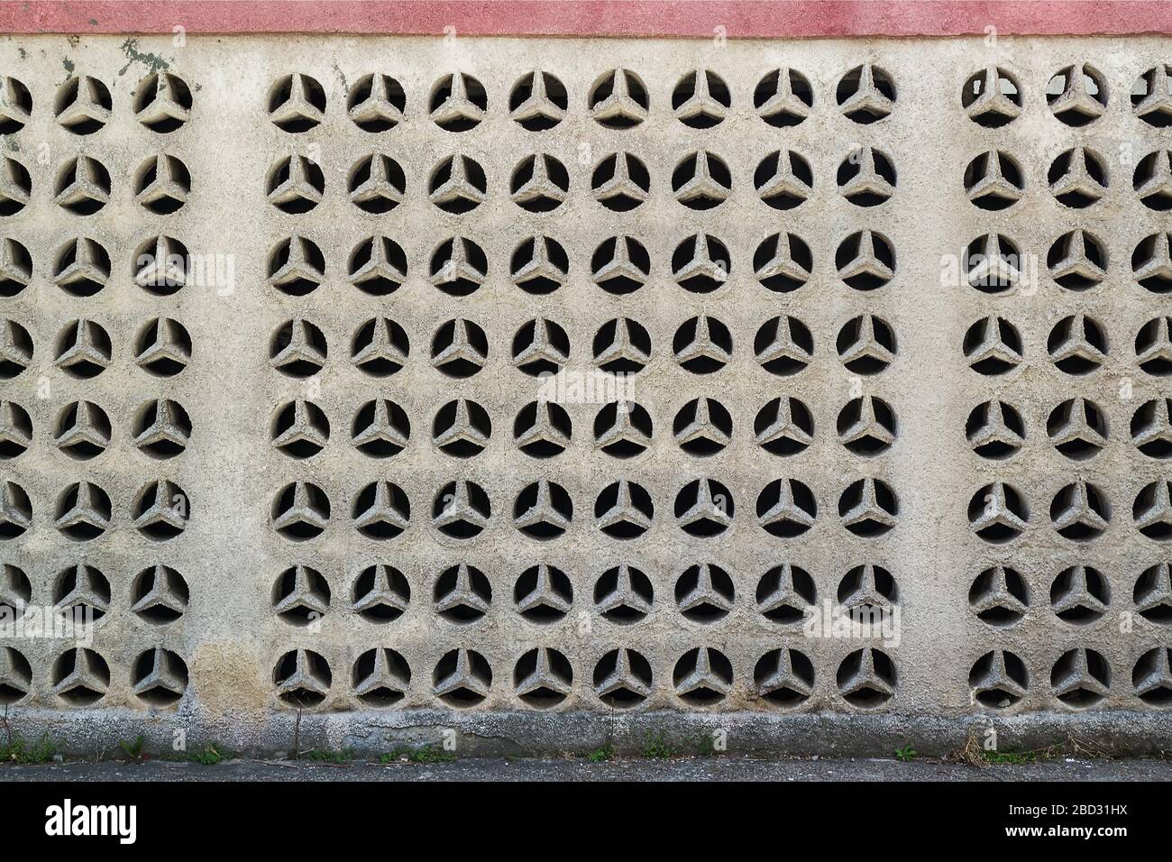 Dekorative Außenwand aus offenen Betonplatten oder Blöcken mit geometrischem Repetiermuster als Hintergrund. Architektonischer Retro-Stil. Stockfoto
