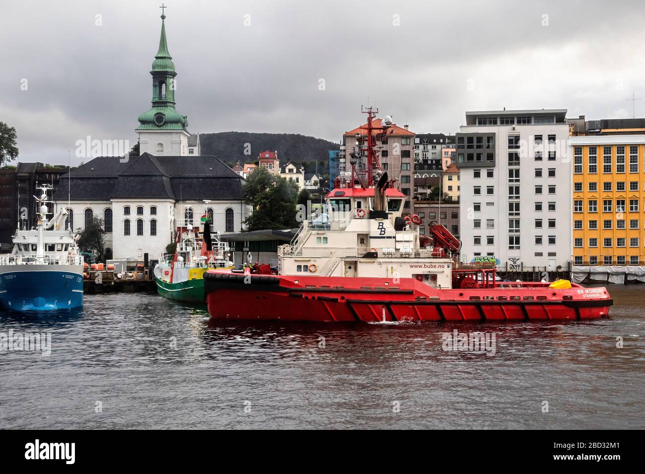 Schleppboot BB Arbeiter im Hafen von Bergen, Norwegen. Ein regnerischer und regnerischer Tag, Angelschiff Skagoeysund, Tauchschiff Octopus und Nykirken Kirche in BA Stockfoto