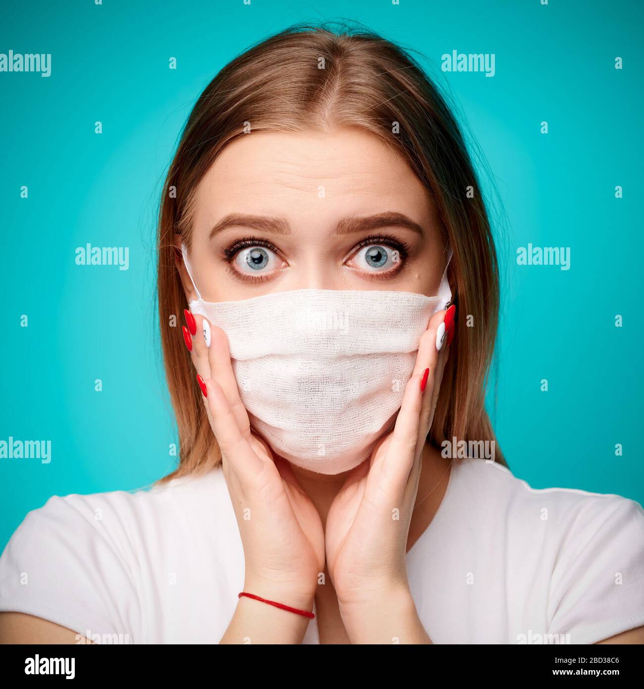 Überraschte Frau in aseptischer Maske in isoliertem blauem Hintergrund. Covid19, Virus, Pandemie-Konzept Stockfoto