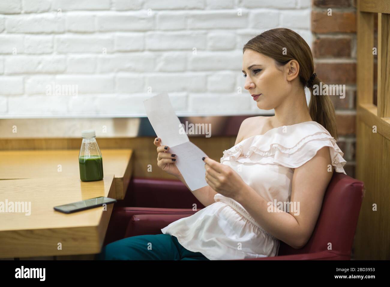 Eine junge Frau liest einen Brief im Café Stockfoto