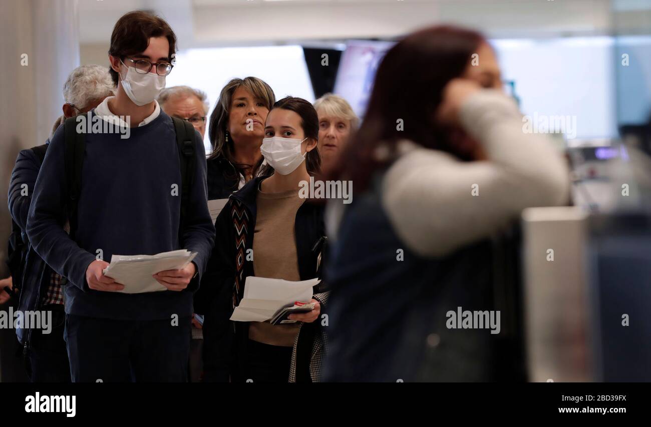 Beamte des US-amerikanischen Zoll- und Grenzschutzamtes für Feldeinsätze sehen internationale Passagiere aus, die am Dulles International Airport in Dulles, Virginia, am 13. März 2020 ankommen. Als Reaktion auf die Coronavirus-Pandemie (COVID-19) haben CBP-Beamte begonnen, persönliche Schutzausrüstung (PSA) zu tragen, während sie mit Passagieren interagieren, die aus dem Ausland ankommen. Viele Passagiere haben auch PSA gespendet, um sich und andere auf ihren Reisen zu schützen. CBP Foto von Glenn Fawcett Stockfoto