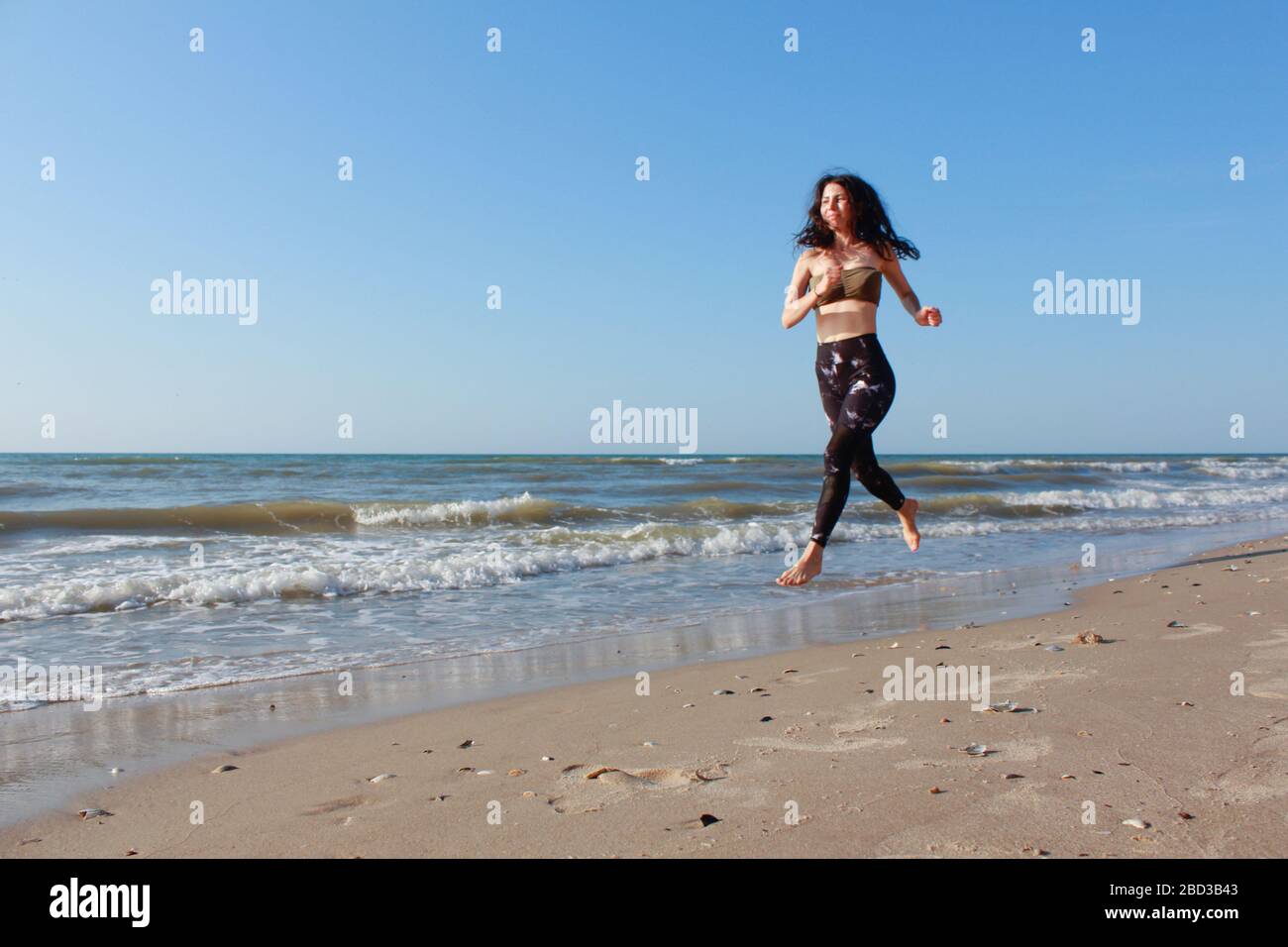 Sportliches Mädchen Training draußen. Sie läuft am Meer. Athletic Fitness Woman, die am Strand läuft. Laufbuchse Jogging. Outdoor-Workout. Fitness Stockfoto