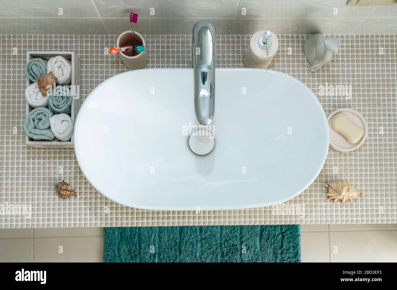 Waschbecken und persönliche Hygieneartikel wie Zahnbürsten, Seife und Handtuch im Bad. Stockfoto