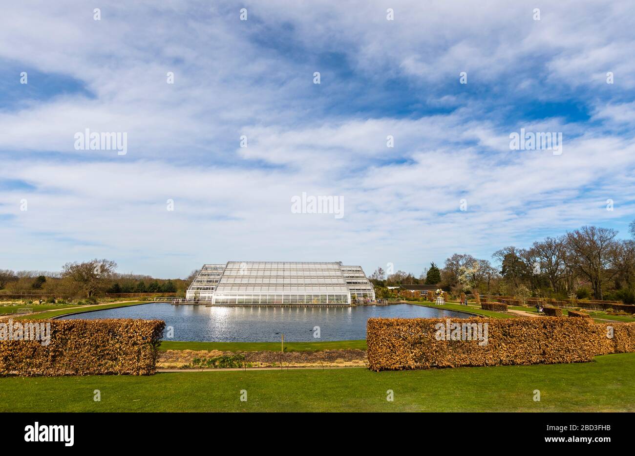 Die moderne Architektur Glasshouse im RHS Garden, Wisley, Surrey im Frühling mit trübem blauem Himmel Stockfoto