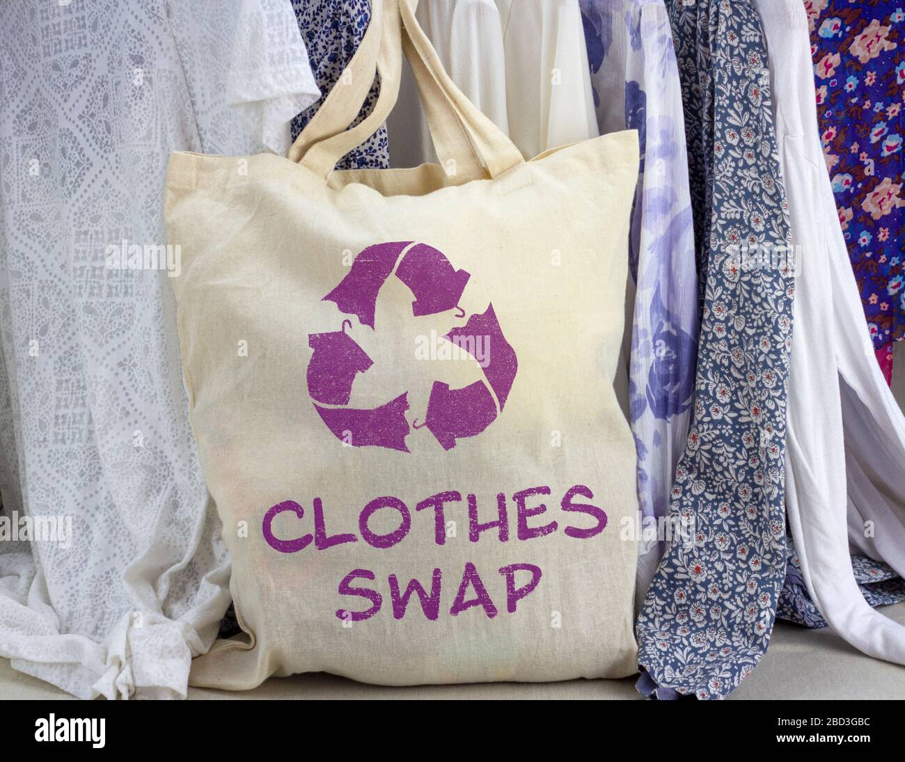 Kleidung tauschen wiederverwendbare Tüten gegen Recycling-Textilien-Symbol vor dem Kleiderrahmen aus. Recyceln Sie Kleidung für ein nachhaltiges Leben. Stockfoto
