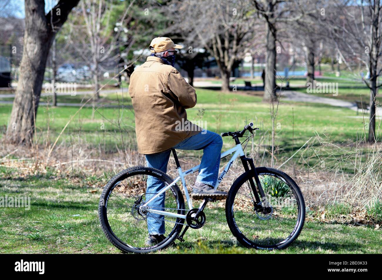 St. Charles, Illinois, USA. Ein älterer Mann, ausgestattet mit einer Bandanna als Gesichtsmaske, pausiert seine Radtour in einem Park. Stockfoto