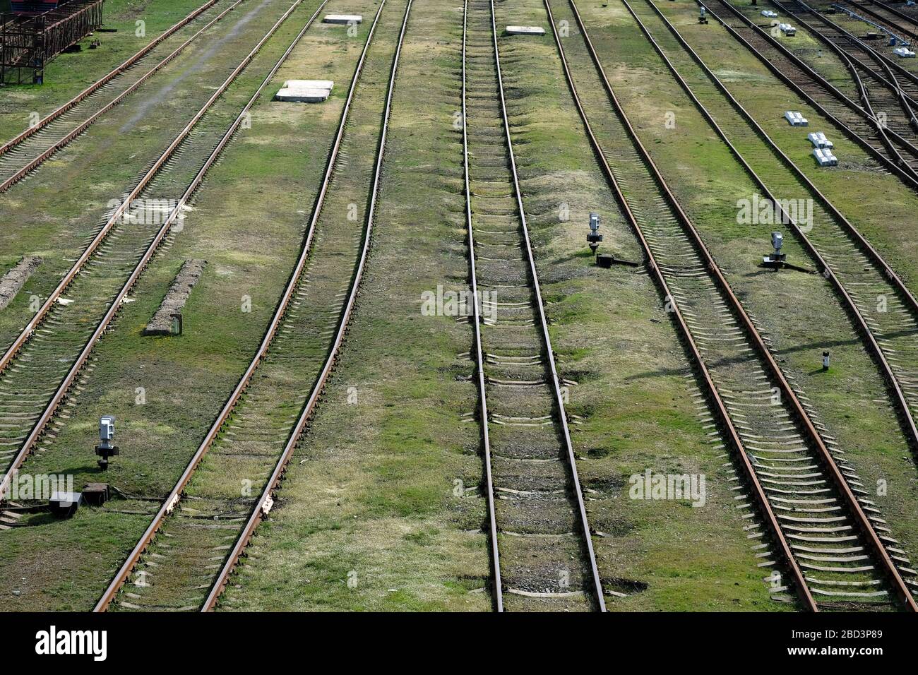 Leere Bahngleise von oben. Verlassene Bahngleise. Bahnschienen auf grünem Gras. Anhalten von Zügen während der Quarantäne. Stockfoto