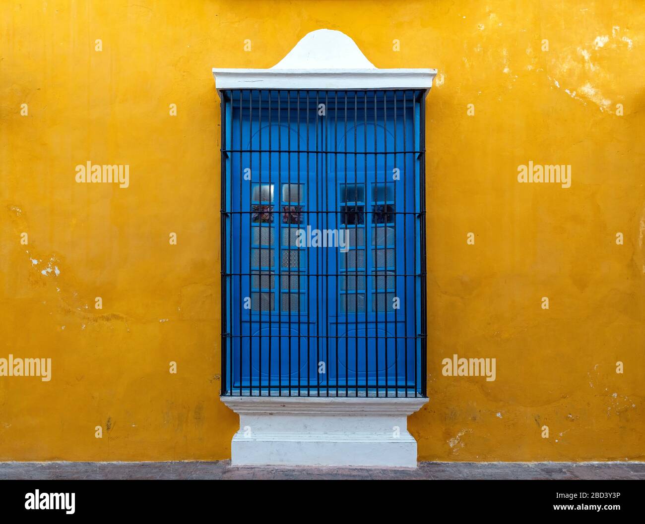 Ein blaues Fenster an einer gelben Wand, eine bunte Fassade im historischen Stadtzentrum von Campeche, Yucatan-Halbinsel, Mexiko. Stockfoto