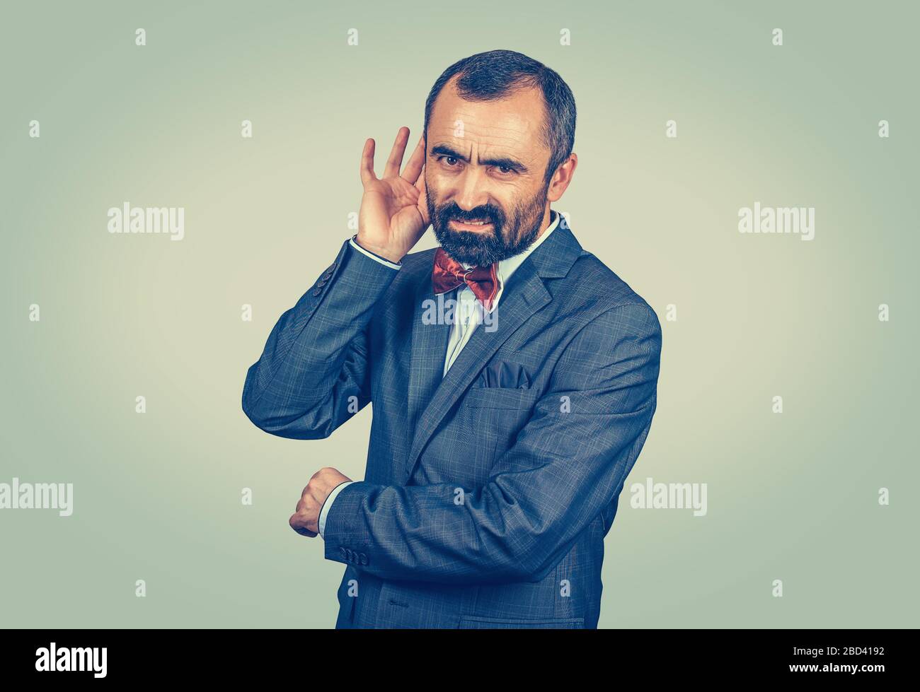 Unzufriedener Schwerhöriger, der die Hand auf das Ohr legt und jemanden auffordert, sich zu äußern oder schlechte Nachrichten zu hören, isoliert auf grüngelbem Gradientenhintergrund. Neg Stockfoto