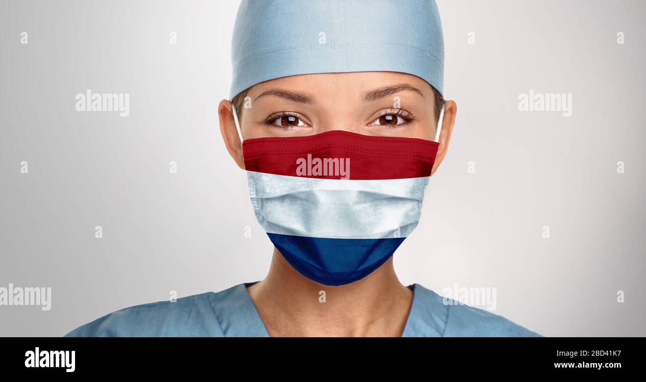 Niederlande COVID-19 Coronavirus Konzept. Holländische Flagge auf dem medizinischen Gesichtsmaskenaufdruck des glücklichen asiatischen Arztes für eine gute Hoffnung auf Genesung. Stockfoto