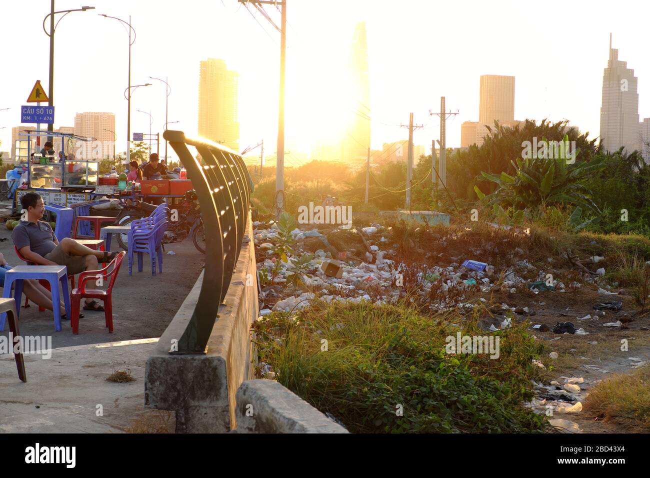 HO CHI MINH STADT, VIET NAM, Menschen sitzen im Freien Café auf Brücke Bürgersteig, über Geländer in Müll, Plastiktüte, Umweltverschmutzung Stockfoto