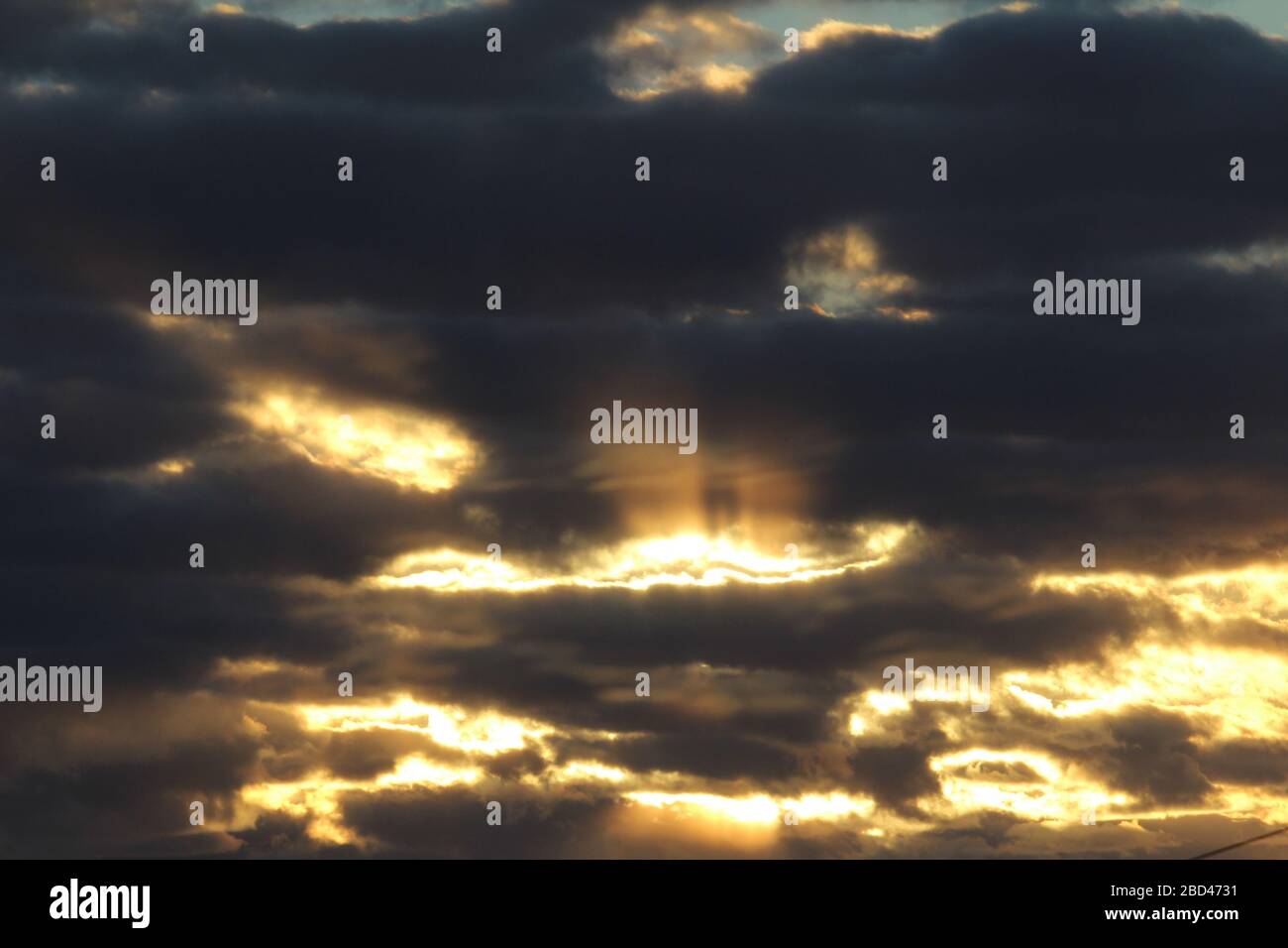 Die Sonnenstrahlen durchziehen die dunklen Wolken. Wunderschöner dramatischer Himmel bei Sonnenuntergang oder Sonnenaufgang. Stockfoto