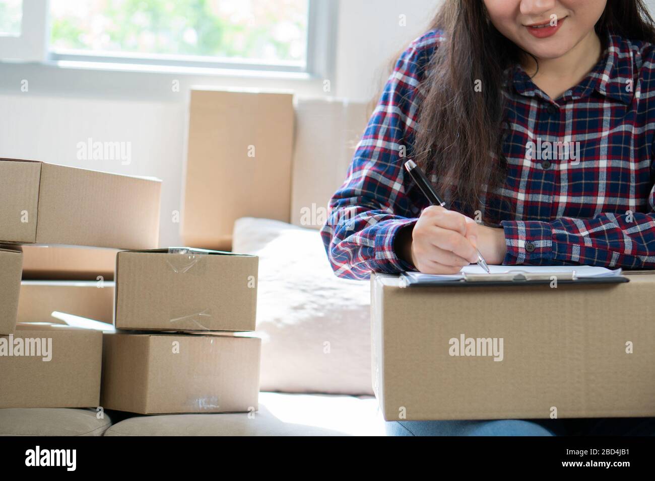Junge Frau Unternehmer, auf dem Sofa sitzen und arbeiten zu Hause. Die Aufnahme der Jahresumsatz und die Planung auf Strumpf Produkte zur Lieferung Versand onl Stockfoto