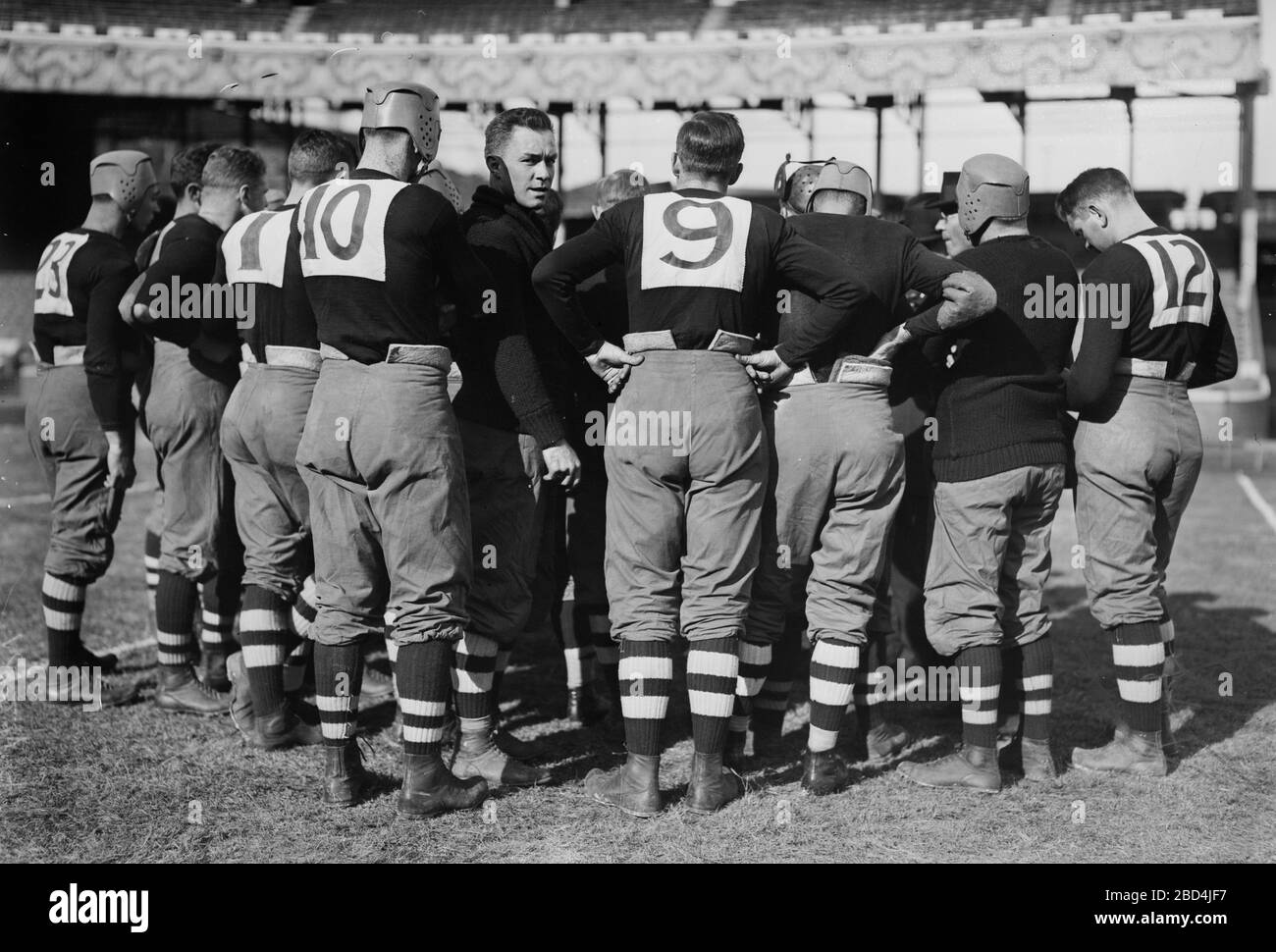 Huddle von Spielern für das Footballteam der Brown University, darunter: Left Guard William Wallace Wade (1892-1986) (Spieler Nr. 10) und linken Tackle Walter Kenneth Sprague, (Spieler Nr. 9) während des Spiels gegen Cornell, das am 24. Oktober 1914 auf dem Polo Grounds (Brush Stadium) in New York City ausgetragen wurde Stockfoto