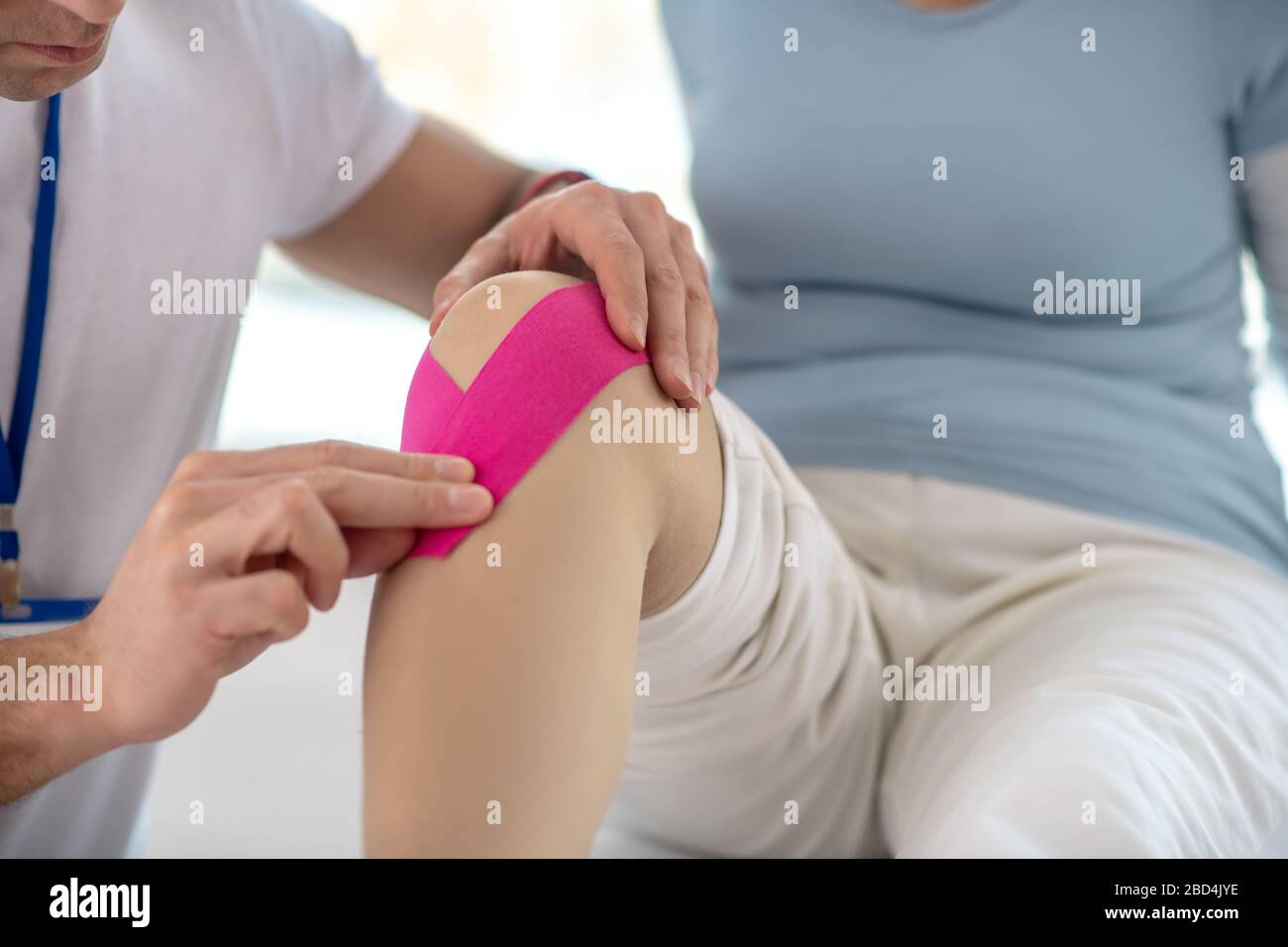 Nahaufnahme eines rosafarbenen Bandes am weiblichen Knie Stockfoto
