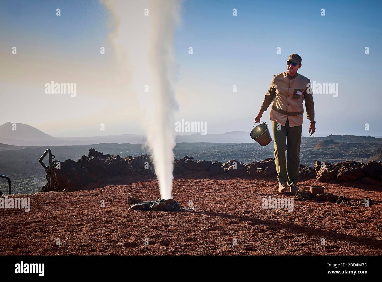 Ein Mitarbeiter des Timafaya National Parc demonstriert die unterirdische Hitze. Ein in ein Loch gepudertes, keilfertiger Wasser erwärmt sich und schießt wie ein Geysir Stockfoto