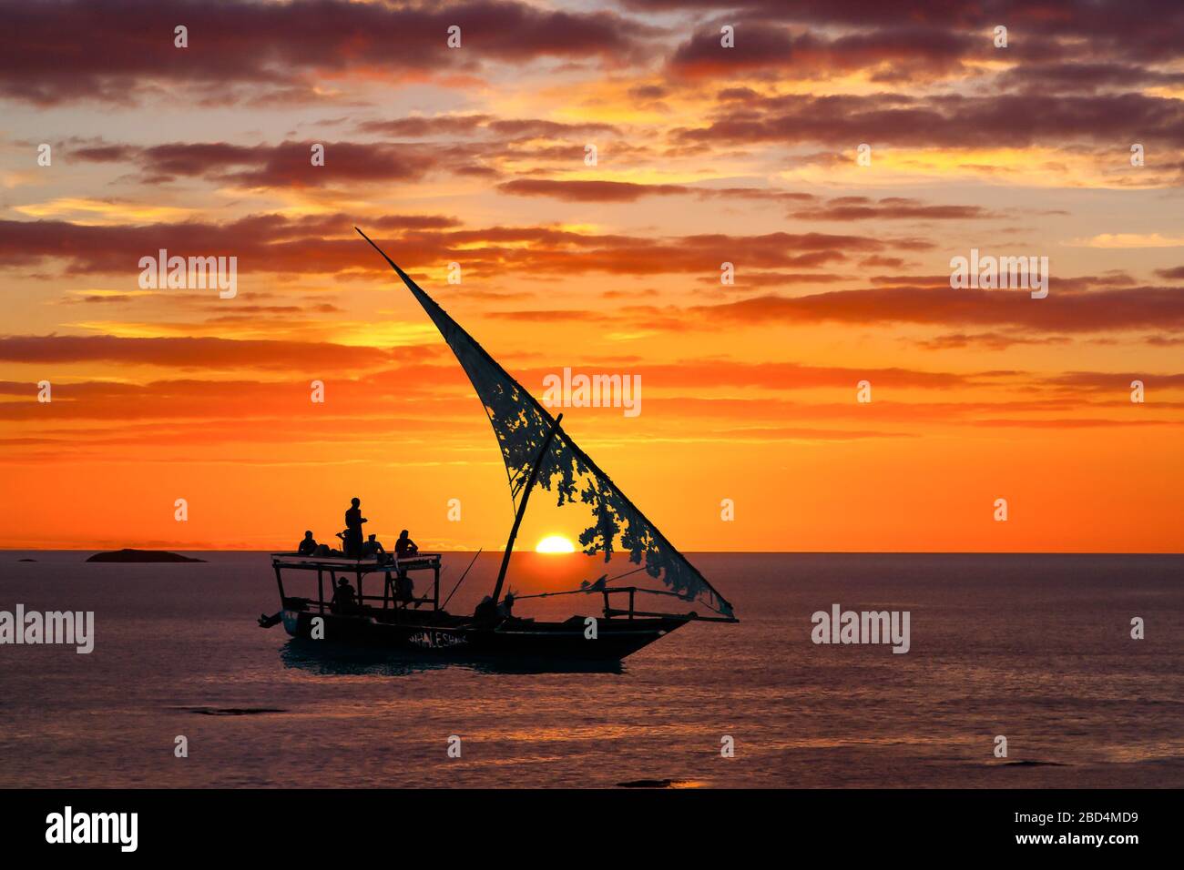 Dies ist ein zusammengesetztes Foto eines schottischen Sonnenuntergangs, der mit einem afrikanischen Dow-Segelboot vor der Küste von Stone Town Sansibar vermischt wurde Stockfoto