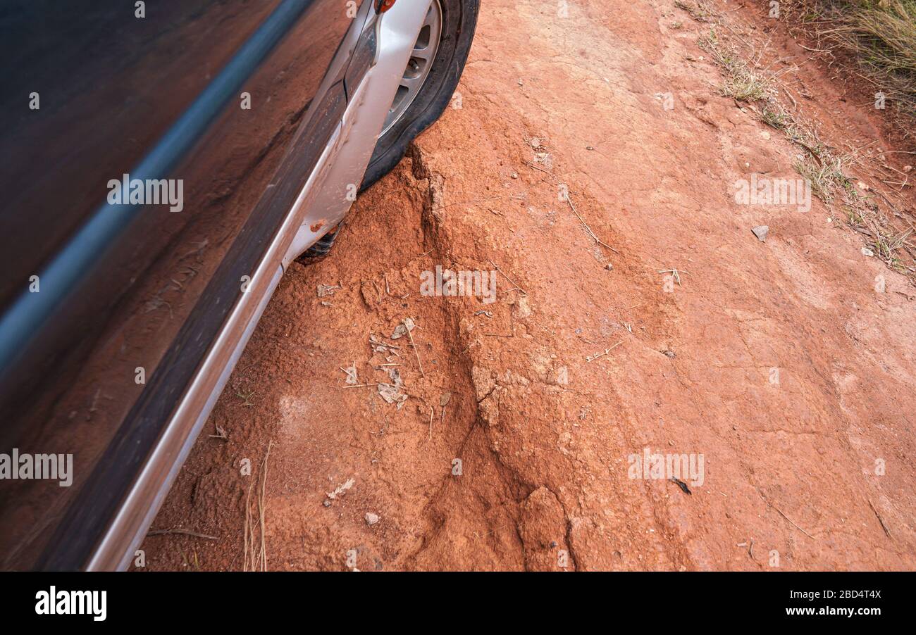 geländewagen auf rot staubiger Landstraße mit großen Löchern fahren, Details auf Reifen mit geringem Druck über unebenes Gelände. Die Straßen sind in schlechtem Zustand Stockfoto