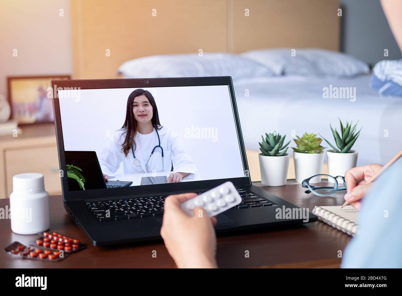 Kranke Frau nutzt Videokonferenz, macht Online-Rücksprache mit Arzt über Laptop, Patient fragt Arzt über Krankheit und Medikamente per Video c Stockfoto