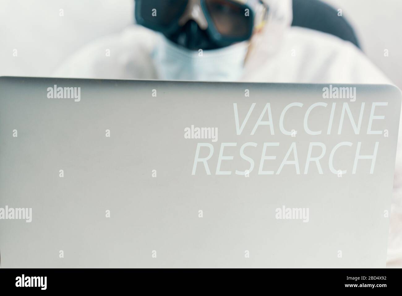 Bio Hazard man mit Laptop. Mann, der einen Laptop auf einem Quarantänetabelle verwendet. Stockfoto