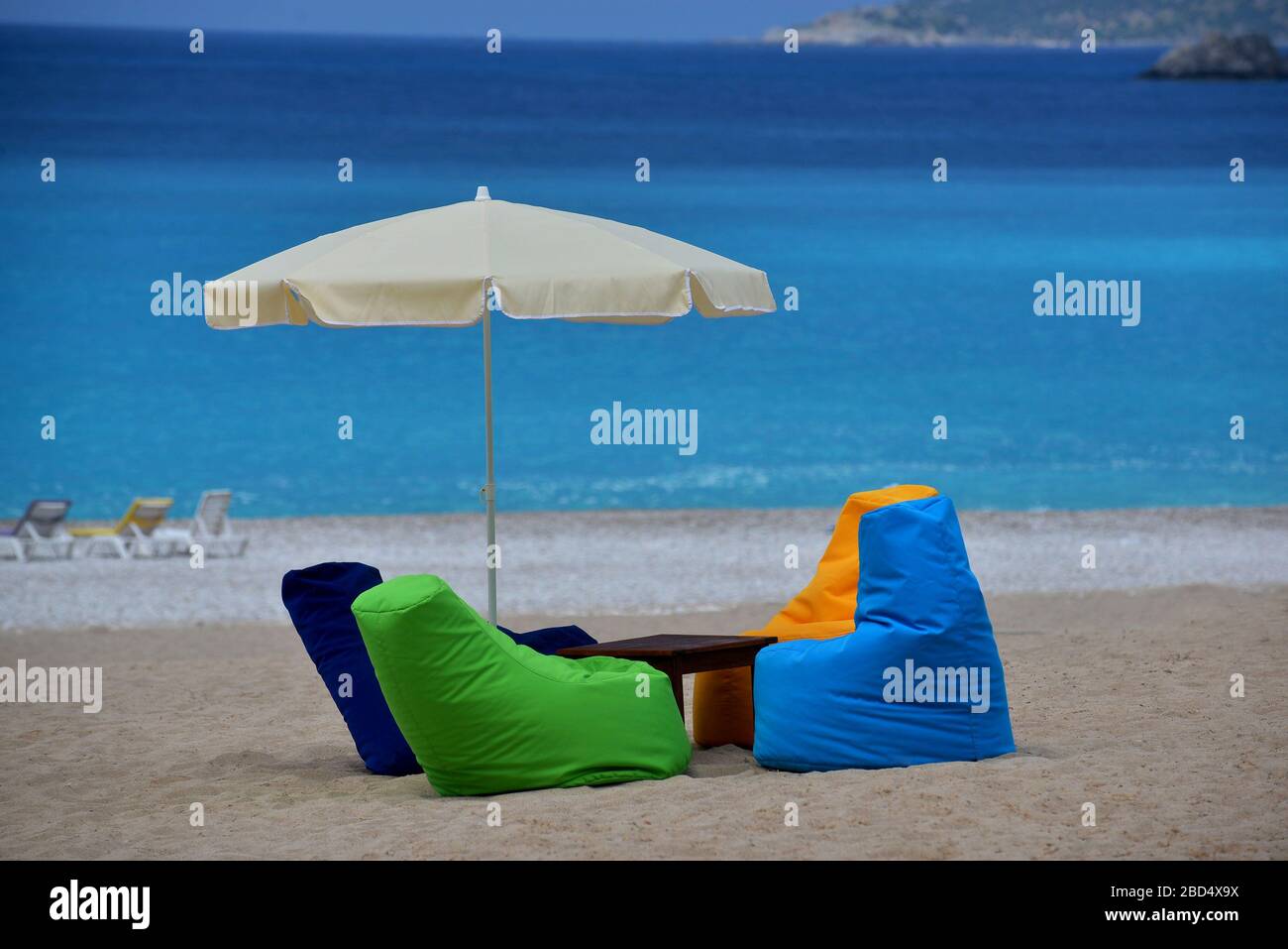 Helle, bunte Sitze und Sonnenschirm befinden sich am Strand. Blaues Meer ist im Hintergrund. Dies ist ein Sand-Strand ausgestattet. Stockfoto