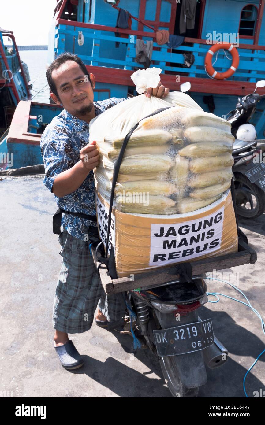 dh Port of Benoa BALI INDONESIA Indonesian lokaler Mann, der heissen Mais auf dem Motorrad aus Asien verkauft Stockfoto