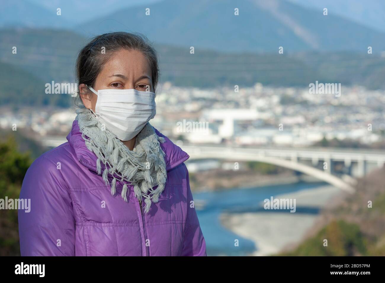 Schöne Frau mittleren Alters mit einer weißen Maske zum Schutz vor Coronavirus COVID-19 (SARS-COV-2) und anderen ansteckenden Krankheiten. Stockfoto