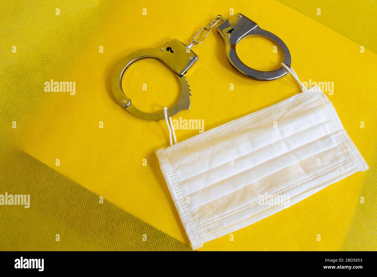 Das Konzept einer medizinischen Maske und Handschellen. Operationsmaske mit Gummi-Ohrbändern. Typische 3-lagige Operationsmaske zur Abdeckung von Mund und Nase. Stockfoto