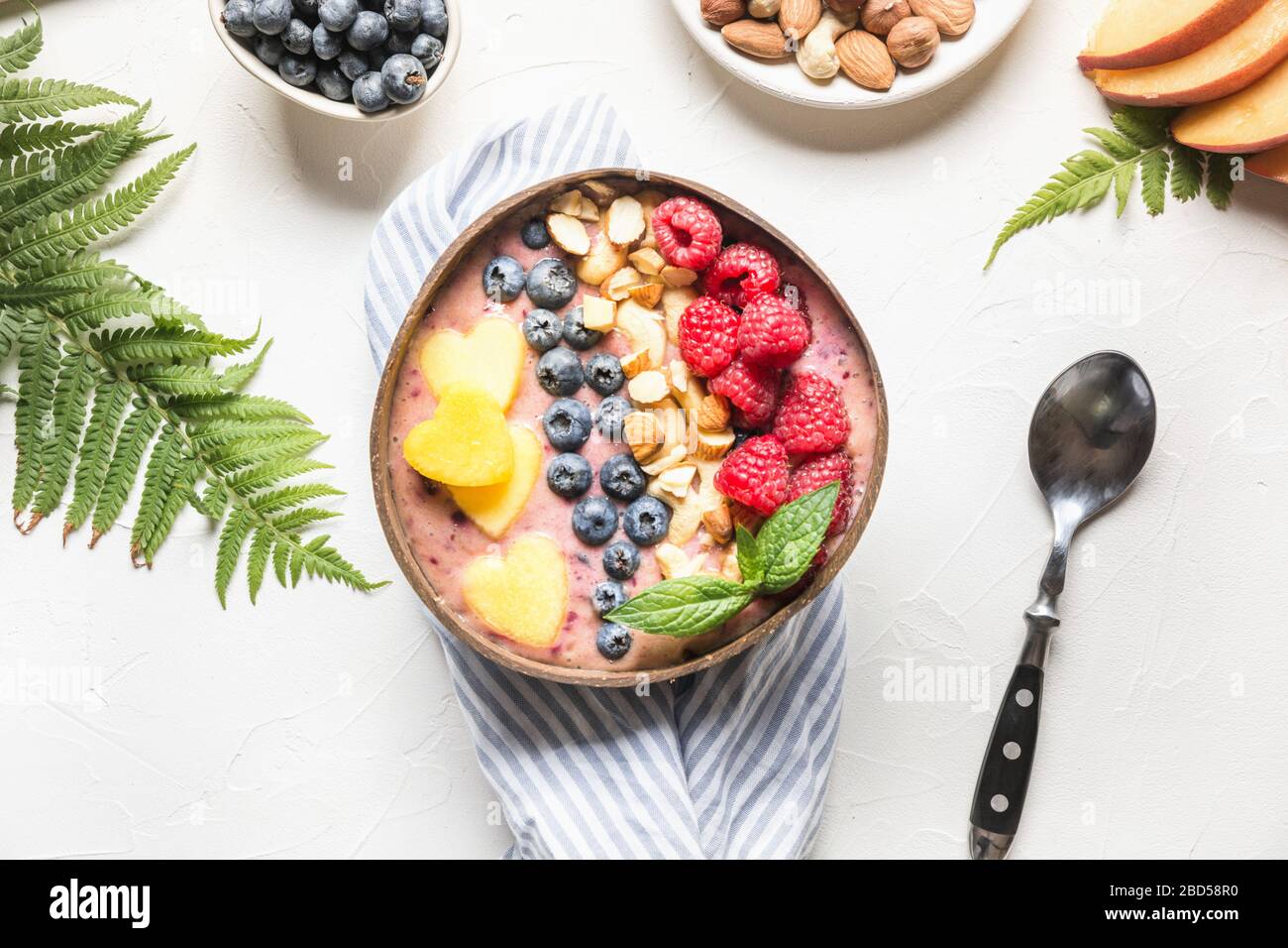 Banane und Blaubeere Smoothie auf Weiß. Gesundes Frühstück in der Kokosschale. Ansicht von oben mit Kopierbereich. Sauberes Essen, vegetarisches Essen. Stockfoto