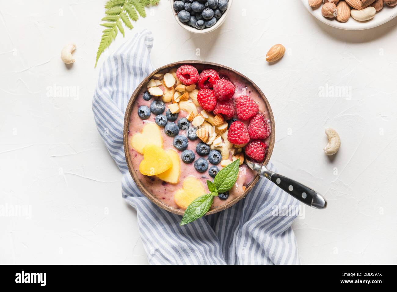 Banane und Blaubeere Smoothie auf Weiß. Gesundes Frühstück in der Kokosschale. Ansicht von. Sauberes Essen, vegetarisches Essen. Stockfoto