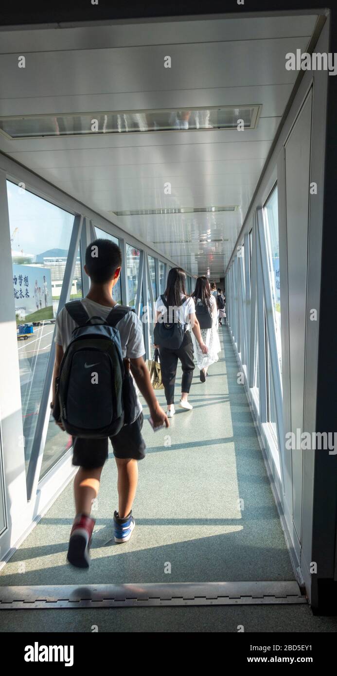 Passagiere, die mit dem Flugzeug durch den Gehweg, den Flughafen Hangzhou, China, einsteigen Stockfoto