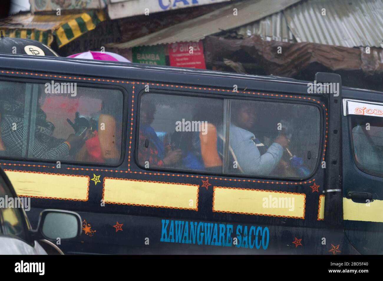 Menschen, die auf dem Weg zur Arbeit sind, fahren an einer Bushaltestelle bei starkem Regen, Nairobi, Kenia. In Kenia sind viele Busse im Besitz von SACCO (Savings and Credit Co-ope) Stockfoto