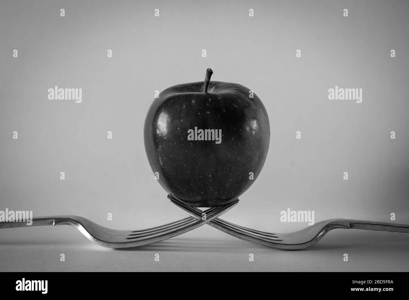 Roter apfel auf zwei Gabeln, Schwarzweiß Stockfoto