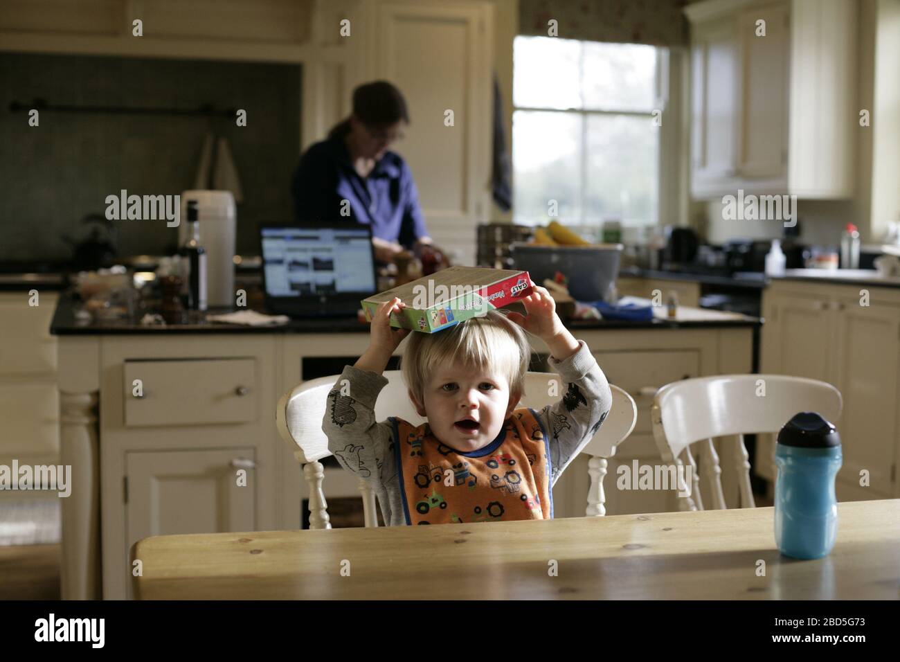 Kind Kleinkind spielen mit Puzzle während Mutter Kochen Abendessen in der Küche während der Zeit der Selbstisolation - 2020 COVID-19 Coronavirus Pandemie Stockfoto