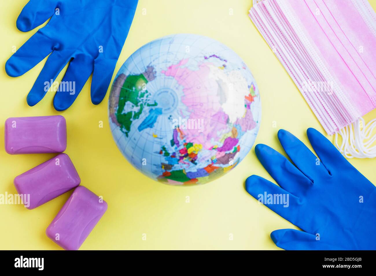 Globus, medizinische Masken, Handschuhe und Seife im Hintergrund. Stockfoto