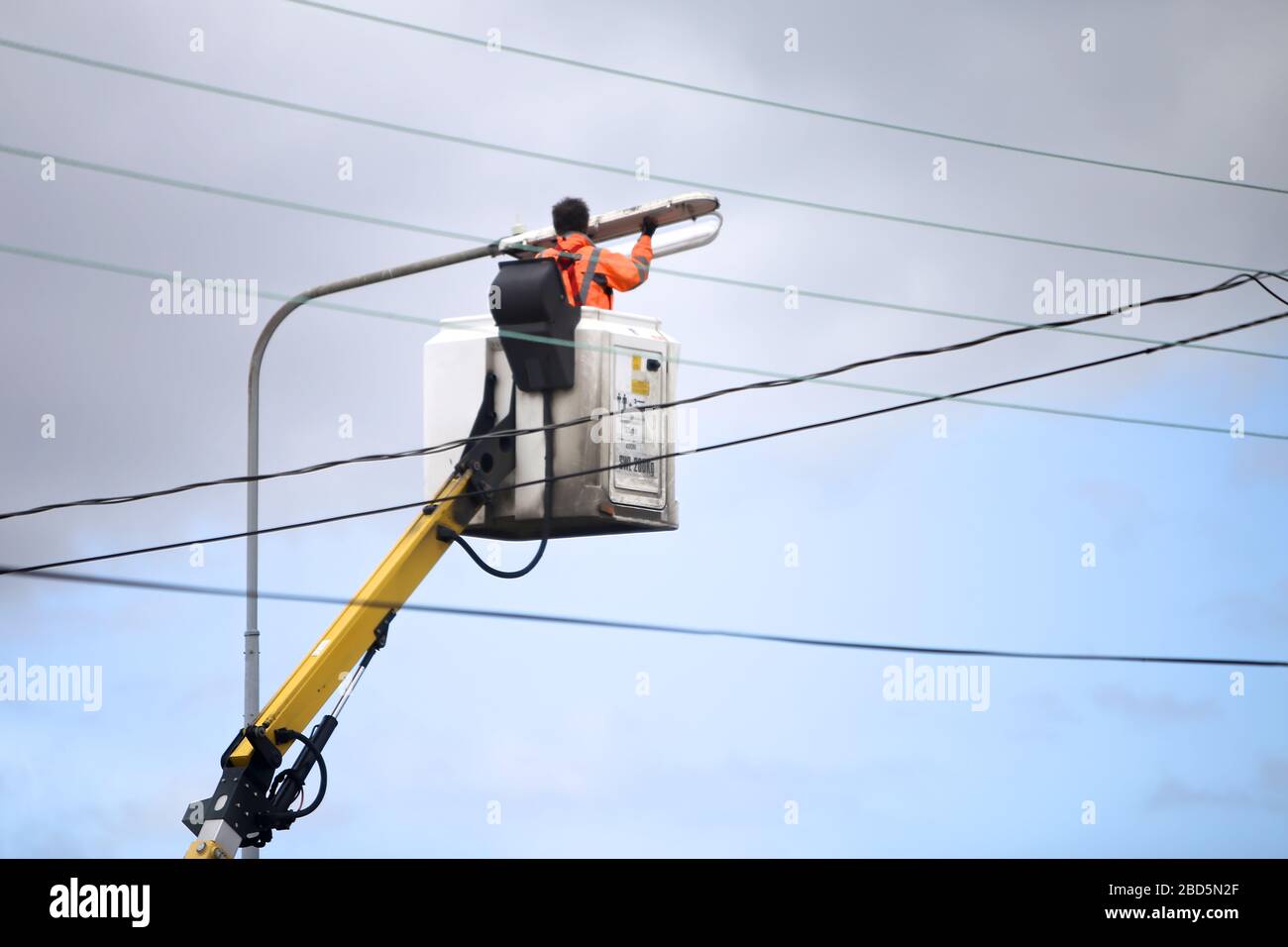 Ein Mann, der die Lichteinbringung in einer Straßenleuchte ersetzt. Stockfoto