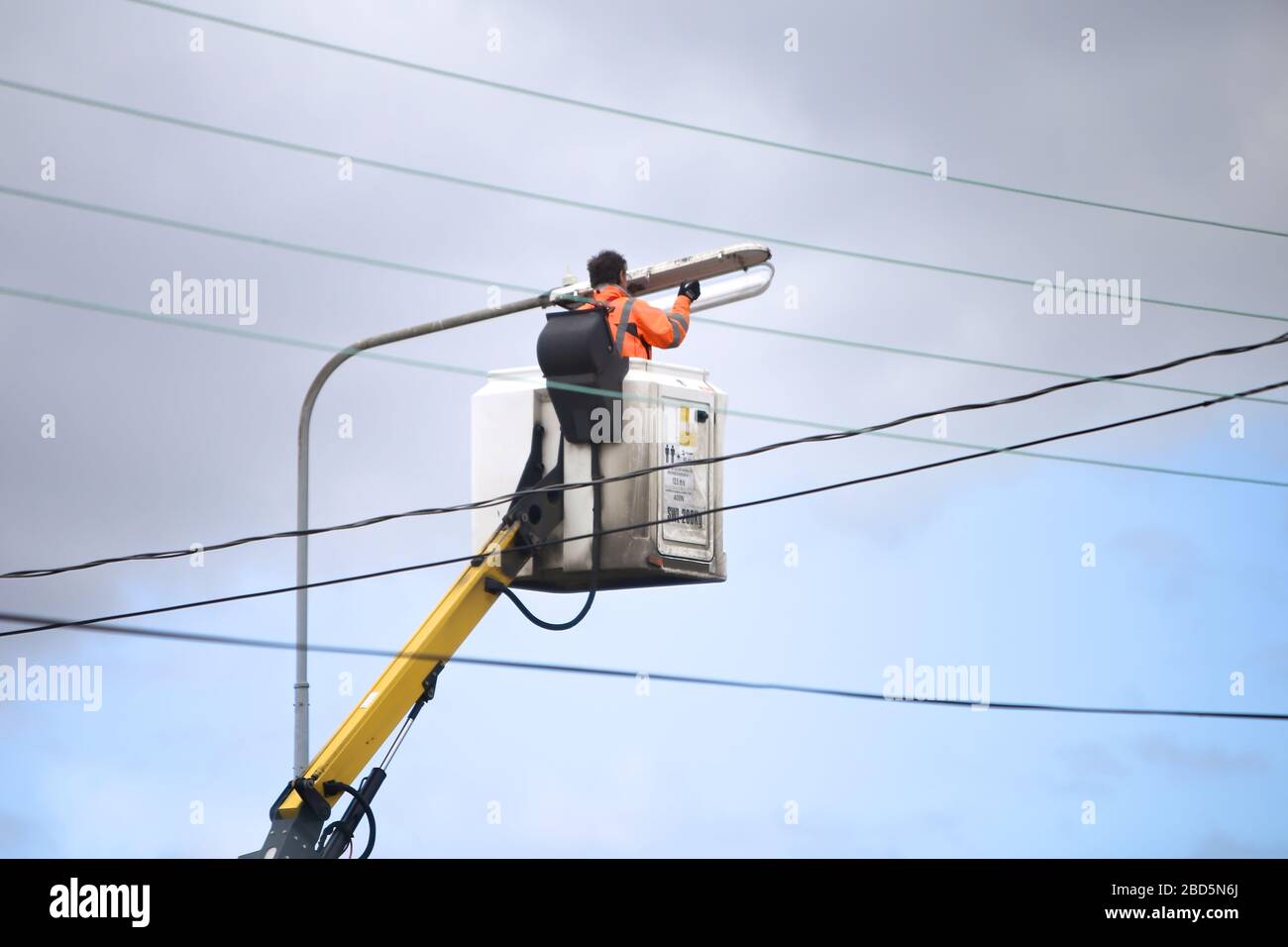 Ein Mann, der die Lichteinbringung in einer Straßenleuchte ersetzt. Stockfoto