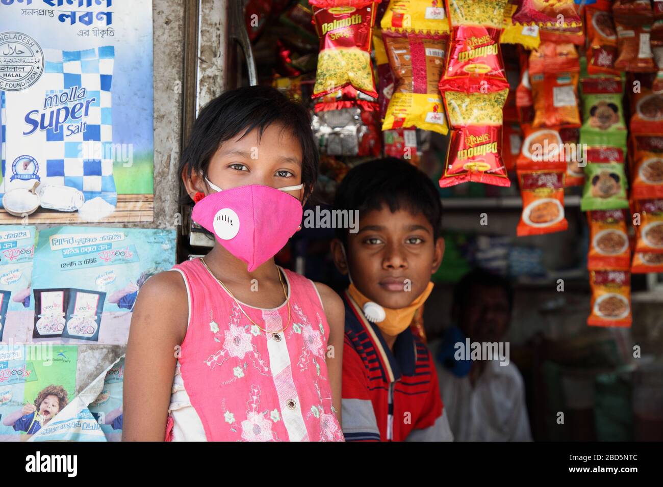 Dhaka, Bangladesch. April 2020. April 2020: Ein kleines Mädchen trägt Gesichtsmaske und hilft seinem Vater beim Verkauf der Lebensmittel im Lebensmittelgeschäft, neben ihrem weiteren kleinen Jungen, der jetzt auf einem kleinen Basar in Dhaka, Bangladesch, im Dienst ist, Während der landesweiten Notabsperrung, um die weit verbreitete Coronavirus Covid-19-Krankheit zu stoppen. Kredit: ZUMA Press, Inc./Alamy Live News Stockfoto