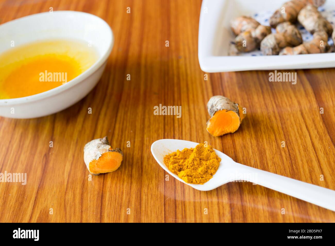 Ein Tischlöffel aus reinem turmerischem Haldi-Gewürzpulver. Kurkuma mit Wasser. Entgiftung oder Entgiftung. Gesundheitspflege und medizinische Ernährung Stockfoto