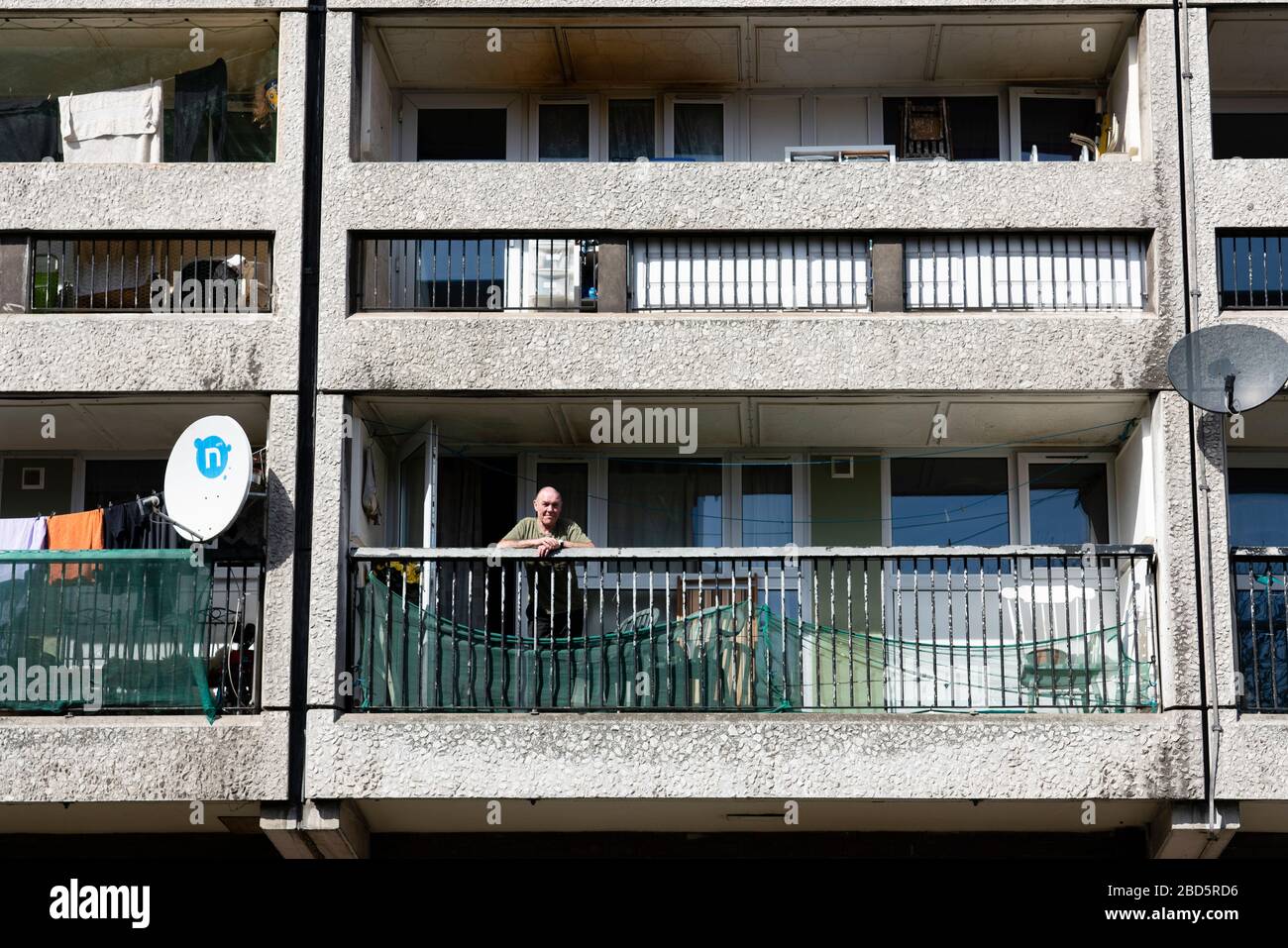 Leith, Edinburgh, Schottland, Großbritannien. April 2020. In der dritten Woche des landesweiten Coronavirus Sperrlebens in Leith geht es weiter, obwohl die Straßen meist verlassen sind und Geschäfte geschlossen sind. Abgebildet; älterer Mann auf Balkon in seiner Wohnung in Kabeln Wynd House Apartmentblock. Stockfoto