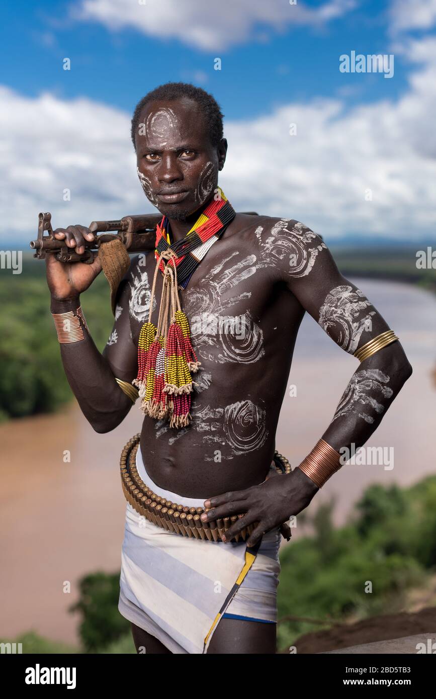 Mit seinem Gewehr und seiner Körperfarbe hoch über dem Omo River, einem Karo-Stamm oder ethnischen Gruppenmitglied, Tumi, Äthiopien. Stockfoto