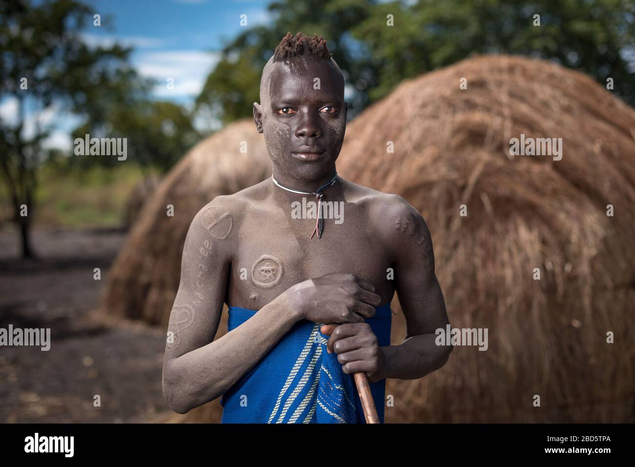 Mit ornamentalen Narben und Gehstab, ein junger Mann des Stammes oder der ethnischen Gruppe Mursi, Dorf Olikoru, Jenka, Äthiopien. Stockfoto