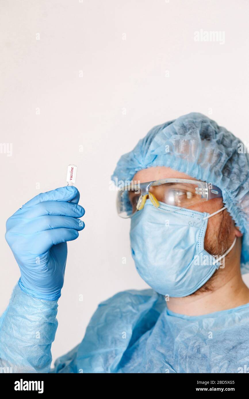 Nahaufnahme des Impfstoffs zur Handhaltung des Arztes. Medizinische Geräte. Ein Arzt, der persönliche Schutzausrüstung trägt, einschließlich Maske, Schutzbrille und Schutzkleidung Stockfoto