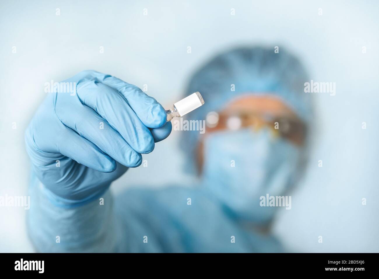 Nahaufnahme des Impfstoffs zur Handhaltung des Arztes. Medizinische Geräte. Ein Arzt, der persönliche Schutzausrüstung trägt, einschließlich Maske, Schutzbrille und Schutzkleidung Stockfoto