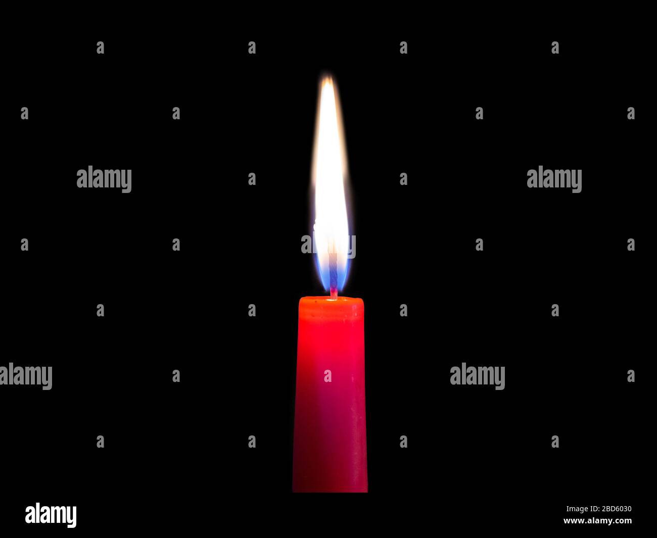 Nahaufnahme einer rot brennenden Kerze mit weiß-blauem Feuer auf schwarzem Grund Stockfoto