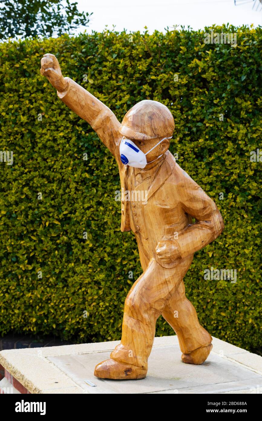 "Clockpelter"-Statue, die während der Covid-19-Corona-Virus-Pandemie eine medizinische Gesichtsmaske trägt. Great Gonerby, Grantham, Lincoln, England. April 2020 Stockfoto